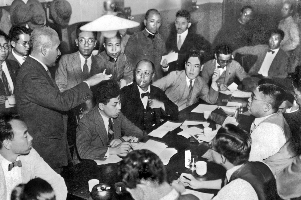 1932年10月、陸軍省新聞班長(左)から国際連盟リットン調査団の報告書についての発表を聞く記者たち(日本電報通信社撮影)