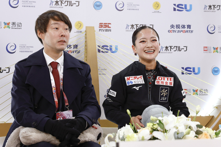 女子SPの得点を確認し、笑顔の渡辺倫果。左は中庭健介コーチ=重慶(共同)