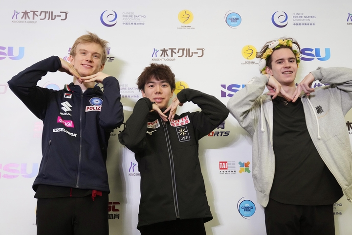 記者会見でポーズをとる優勝した佐藤駿。左は2位のダニエル・グラッスル、右は3位のミハイル・シャイドロフ=重慶(共同)