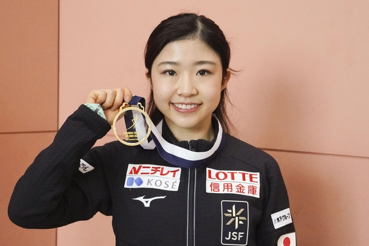 帰国し、撮影に応じるフィギュアスケート女子の千葉百音=24日、関西空港