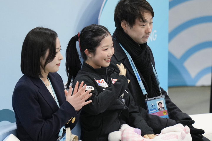 女子SPの得点を確認し、笑顔の中井亜美(中央)。奥は中庭健介コーチ=北京(共同)