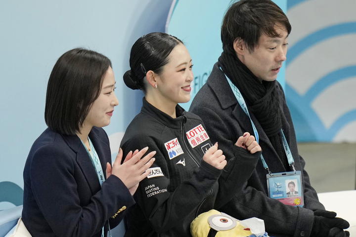 女子SPの得点を確認し、笑顔の青木祐奈(中央)。奥は中庭健介コーチ=北京(共同)