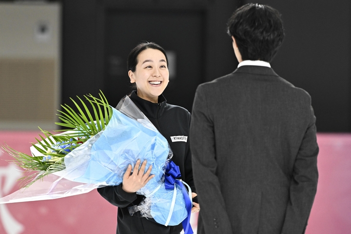 木下グループの入社式で、島田高志郎(手前)に花束を手渡す浅田真央さん=13日、東京都立川市