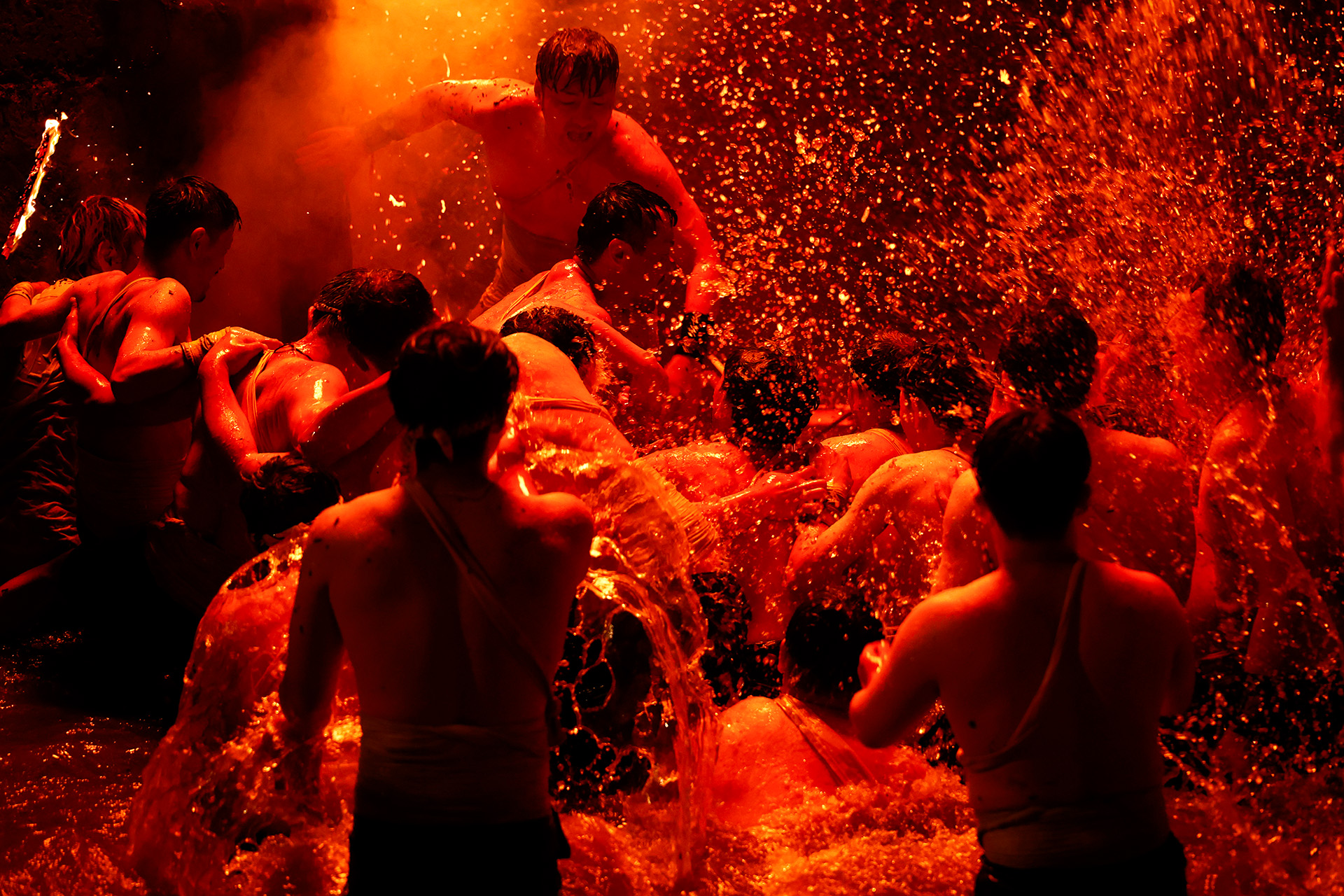 オレンジ色の火の粉が舞う中、男衆がみこしを川へ投げ込む能登町のあばれ祭